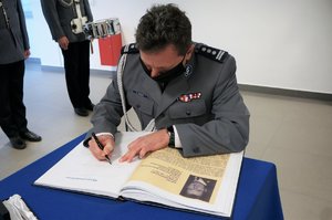 Komendant z Raciborza dokonuje wpisu do księgi pamiątkowej.