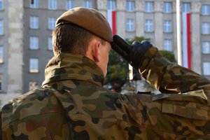 Umundurowany żolnierz w trakcie oddawania honorów, na tle budynku Urzędu Wojewódzkiego