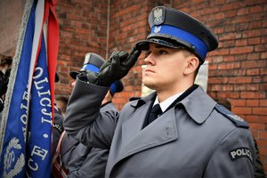 Kolorowe zdjęcie. Policjant oddaje honor.