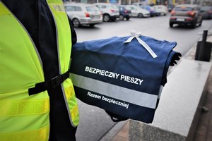 policjant ruchu drogowego trzymający torbę na zakupy z elementem odblaskowym i napisem &quot;Bezpieczny pieszy&quot;