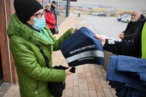 kobieta otrzymuje od policjanta torbę na zakupy z elementem odblaskowym i napisem &quot;Bezpieczny pieszy&quot;