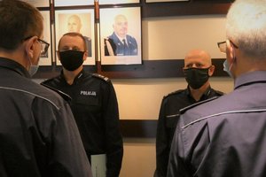 Zdjęcie kolorowe. Widoczni umundurowani policjanci biorący udział w spotkaniu kadrowym w sali portretowej w KWP w Katowicach