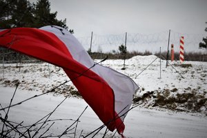 Zdjęcie kolorowe. Widoczna polska flaga, w tle granica