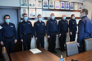 Zdjęcie kolorowe. Widoczni umunudrowani policjanci biorący udział w spotkaniu kadrowym w sali portretowej Komendy Wojewódzkiej Policji w Katowicach