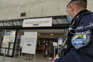 policjant obserwujący punk pomocy dla ukraińców