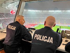 Zdjęcie kolorowe. Widoczni umundurowani policjanci na terenie stadionu