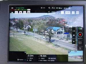 Na zdjęciu widać drogę oraz poruszający się po niej samochód osobowy. Zdjęcie zrobione za pomocą drona wyposażonego w kamerę.