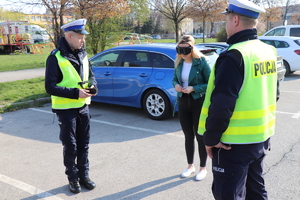 Na zdjęciu widać dwóch policjantów wydziału ruchu drogowego oraz kobietę, która testuje alkogogle imitujące stan po spożyciu alkoholu.