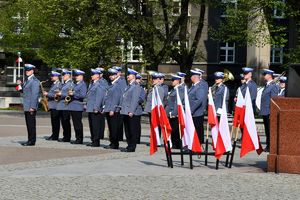 na pierwszym planie w stojakach flagi państwowe w tle orkiestra komendy wojewódzkiej policji w Katowicach