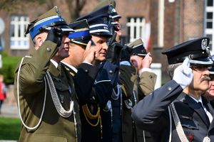zastępca komendanta wojewódzkiego podczas oddawania honoru obok niego stoją przedstawiciele innych służb