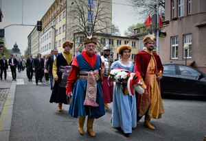 Uczestnicy przemarszu - kobieta i dwóch mężczyzna ubrani w starodawne stroje.