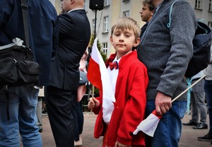 Chłopczyk ubrany na biało-czerwono trzyma w dłoni flagę Polski.