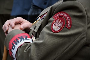 Zbliżenie na naszywkę na mundurze. Widoczny napis Polskie Drużyny Strzeleckie i odznaczenia.