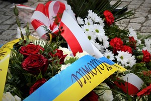 Kwiaty, które złożono pod pomnikiem. Szarfy przy nich mają kolory flagi Polski i Ukrainy.