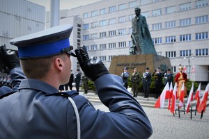 Policjant oddaje honor, przed nim pomnik Wojciecha Korfantego.