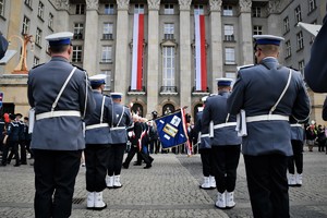 Policyjna orkiestra, w tle Urząd Wojewódzki, na którym zawieszone są biało-czerwone flagi.