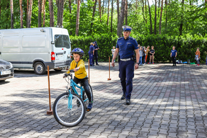 Policjant ruchu drogowego stoi za chłopcem, który jedzie rowerem.