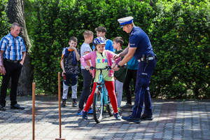 Policjant przytrzymuje kierownicę roweru dziewczynce.