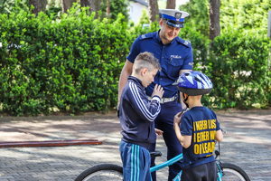 Policjant i dzieci, z których jedno siedzi na rowerze.
