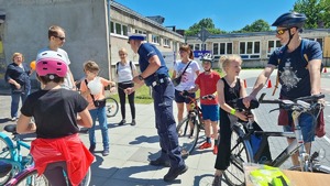 policjant wręczający opaski odblaskowe uczestnikom pikniku