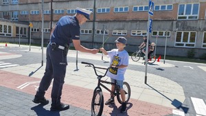 policjant ruchu drogowego wręczający odblask chłopcu na rowerze