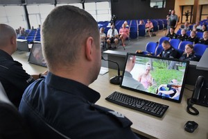 Umundurowany policjant patrzy w monitor, na którym wyświetlany jest spot.
