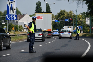 zdjęcie kolorowe: dwóch policjantów ruchu drogowego na ulicy Mikołowskiej zabezpieczający wyścig kolarski