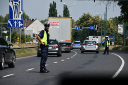 zdjęcie kolorowe: dwóch policjantów ruchu drogowego na ulicy Mikołowskiej zabezpieczający wyścig kolarski