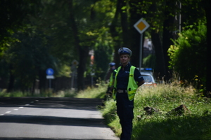 zdjęcie kolorowe:  policjantka zabezpieczająca wyjazd drogi w trakcie wyścigu kolarskiego