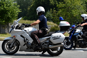 zdjęcie kolorowe: policjanci drogówki na motocyklach w trakcie zabezpieczenia wyścigu kolarskiego