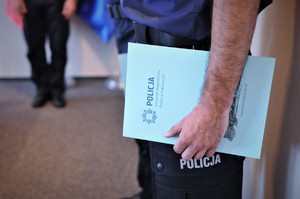 Teczka z rozkazem w dłoniach awansowanego policjanta. Na teczce napis Policja Komenda Wojewódzka Policji w Katowicach i logo.