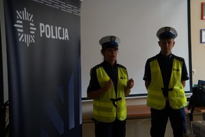 Na zdjęciu widać policjanta i policjantkę, obok baner z napisem policja.
