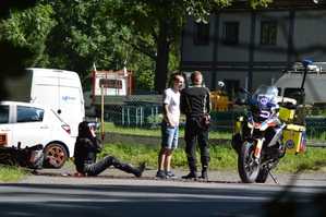 Zdjęcie z miejsca symulowanego wypadku. Na zdjęciu widoczny ratownik medyczny na motocyklu, osoba postronna oraz poszkodowany motocyklista.