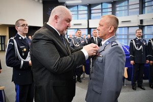 Wicewojewoda przypina medal policjantowi.
