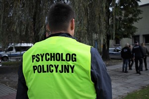 Na zdjęciu policjant w kamizelce z napisem psycholog policyjny.