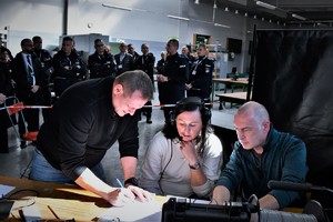Na zdjęciu policyjni negocjatorzy, w tle pozostali uczestnicy ćwiczeń obserwują ich pracę.