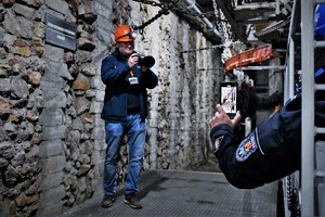 Na zdjęciu widać wnętrze kopalni pod ziemią (korytarz) w prawej stronie jest widoczny policjant robiący zdjęcie telefonem stojącemu w centralnej części policjantowi robiącego zdjęcia aparatem fotograficznym biorący udział w ćwiczeniach.