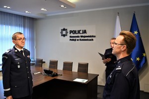 zdjęcie przedstawia Komendanta Wojewódzkiego Policji w Katowicach oraz dwóch innych policjantów  w trakcie odczytywania rozkazu personalnego.