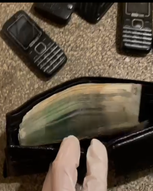 zdjęcie przedstawia saszetkę z pieniędzmi oraz telefony zabezpieczone przy zatrzymanym