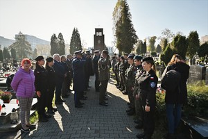 Zdjęcie przedstawia przedstawicieli służb mundurowych oddających hołd na cmentarzu