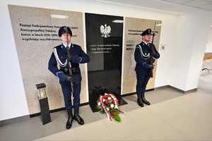 zdjęcie przedstawia asystę honorową przy tablicy pamięci poległych policjantów, składającą się z dwóch policjantów w umundurowaniu galowym