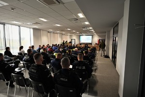 zdjęcie przedstawia zgromadzonych na sali odpraw policjantów w trakcie odprawy służbowej