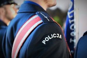 Na zdjęciu fragment policyjnego munduru. Widoczne pagony oraz napis policja.