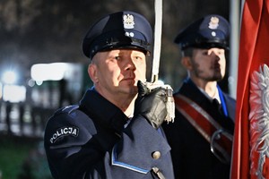 Na zdjęciu policjant trzymający szablę przy twarzy.