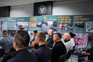 Na zdjęciu uczestnicy szkolenia siedzą w sali Izby Pamięci Narodowej. Przy ścianie kolorowe plakaty z historycznymi wycinkami.