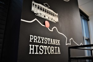 Na zdjęciu ściana, na której widać tramwaj i napis przystanek historia.