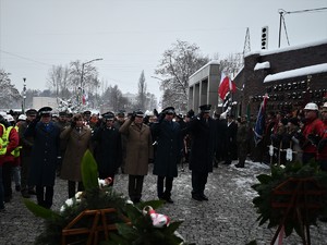 zdjęcie przedstawia mundurowych oddających honor przed pomnikiem.