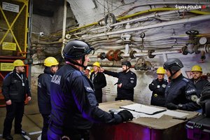 Zdjęcie. Umundurowani policjanci i inne osoby na terenie kopalni pod ziemią