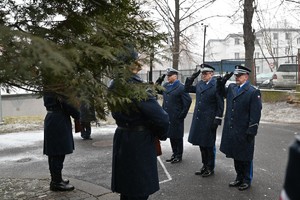 Zdjęcie przedstawia policjantów oddających honor przed tablicą pamiątkową