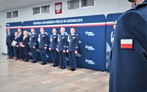 zdjęcie przedstawia zbliżenie na naszywkę z flagą Polski na mundurze policjanta, w tle komendanci wojewódzcy policji